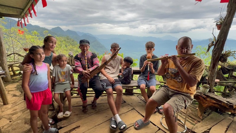 Giàng A La hướng dẫn du khách nước ngoài sử dụng nhạc cụ truyền thống của đồng bào Mông.