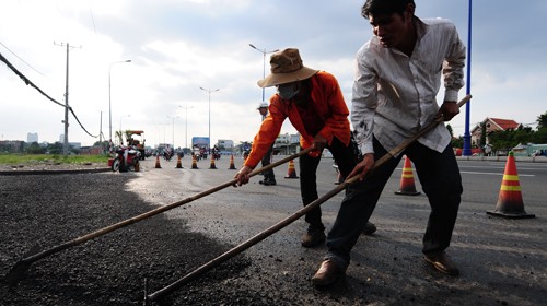 Công nhân thi công trải nhựa trên xa lộ Hà Nội (đoạn Q.2, TP.HCM). Theo kế hoạch, dự án này hoàn thành trong năm 2012 nhưng chậm đền bù giải tỏa nên có thể phải đến năm 2014 mới hoàn thành (ảnh chụp 