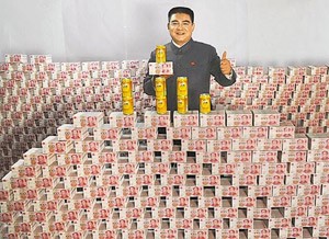 Chen Guangbiao chụp ảnh cạnh "núi tiền" và sản phẩm mới. Ảnh: Xinhua